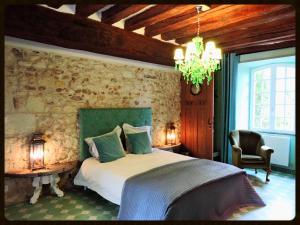 a bedroom with a bed and a stone wall at 'La Ménagerie' in Châteauvieux