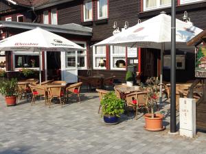 an outdoor patio with tables and chairs and umbrellas at Landgasthof Kleine Kommode in Zorge