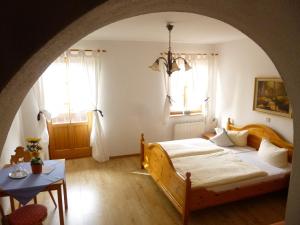 ein Schlafzimmer mit einem Bett, einem Tisch und zwei Fenstern in der Unterkunft Landgasthof Berg in Eurasburg