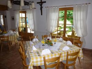 a dining room with tables with yellow and white tablecloths at Landgasthof Berg in Eurasburg