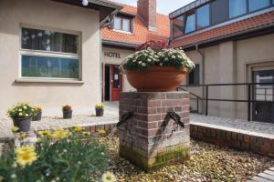 a pot on top of a brick wall with flowers at Landhotel Diana in Teltow