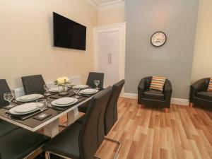 a dining room with a table and chairs and a clock at North Shore Apartment in Blackpool