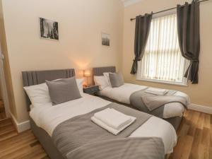 two twin beds in a room with a window at North Shore Apartment in Blackpool