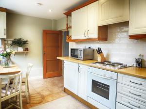 a kitchen with white cabinets and a table with a microwave at The Lansdowne Cottage in Bourton on the Water
