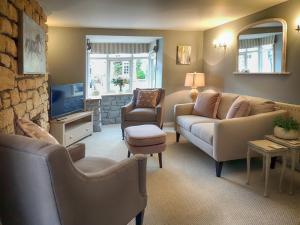 a living room with a couch and chairs and a tv at The Lansdowne Cottage in Bourton on the Water