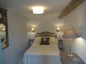 um quarto com uma cama com um candeeiro e uma mesa em La Pagerie em Saint Gatien des Bois