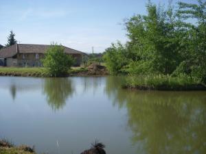 a body of water with a house in the background at Gites Domaine de la Rochere in Domsure
