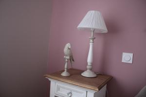 LA PART DES ANGES في Mardeuil: وجود تمثال لطائر يجلس على طاولة بجوار مصباح
