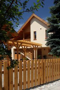 una casa con una valla de madera delante de ella en Family Panzio es Apartman Hazak, en Lipót