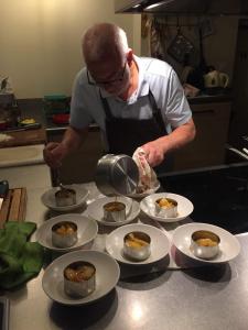 Ein Mann steht in einer Küche und kocht Essen auf Tellern. in der Unterkunft La Pierre d'Eau in Fréland