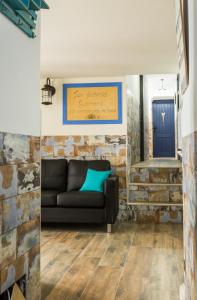 uma sala de estar com um sofá preto e uma parede de tijolos em La posada del Cani em Cómpeta