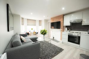 een woonkamer met een grijze bank en een keuken bij Laurel House in Reading