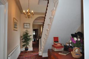 a hallway with a staircase with books on a table at Lower Bryanston Farm in Blandford Forum