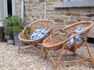 dos sillas de mimbre sentadas una al lado de la otra en un patio en Le 14 St Michel, en Josselin