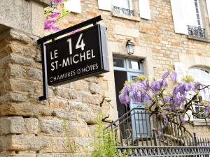 ein Schild an der Seite eines Gebäudes mit lila Blumen in der Unterkunft Le 14 St Michel in Josselin
