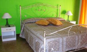 a bedroom with a bed with green walls and two lamps at Ai Limoni in Paceco