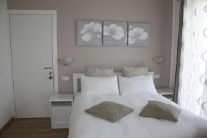 1 dormitorio con 1 cama blanca y 2 almohadas en B&B Le Magnolie, en Faggeto Lario 