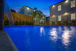 a blue swimming pool in front of a house at Hosteeva Chic Urban Retreat w Pool Steps to St Charles Ave and Near Bourbon St in New Orleans