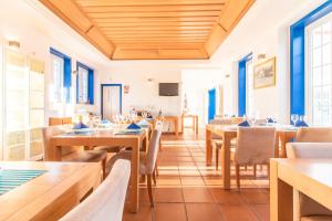 um restaurante com mesas e cadeiras de madeira e janelas azuis em Hotel Lousal em Lousal