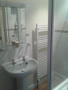 y baño blanco con lavabo y ducha. en Cottage Lea's Country Hotel & Restaurant, en Pickering