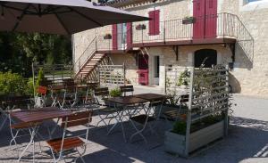 eine Terrasse mit Tischen, Stühlen und einem Sonnenschirm in der Unterkunft LE RELAIS D'ARZAC in Cahuzac-sur-Vère