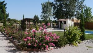 un jardin avec des fleurs roses en face d'une maison dans l'établissement LE RELAIS D'ARZAC, à Cahuzac-sur-Vère