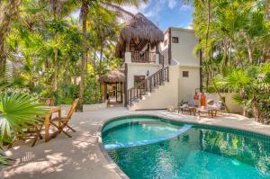 einen Pool vor einem Haus mit Palmen in der Unterkunft Tulum Luxury Collection in Tulum
