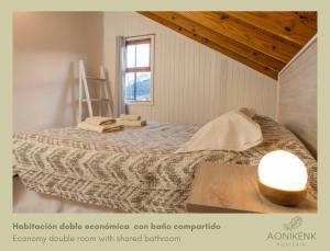 1 dormitorio con 1 cama con mesa y lámpara en Hostería Aonikenk en Ushuaia