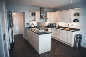 a kitchen with white cabinets and black counter tops at West Gallaton Farmhouse in Stonehaven