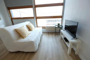 a living room with a white couch and a flat screen tv at Les Studiantes - T1 32 m² hypercentre gares/métro in Lille