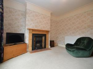a living room with a television and a green chair at Lime House in Newark-on-Trent