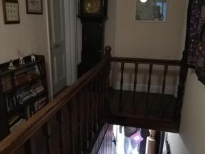 a hallway with a staircase with a clock on the wall at Lion Hotel in Llanbister