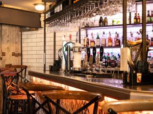 The Lion Pub & Grill في سوويربي بريدج: بار مع كونتر مع كراسي وزجاجات من الكحول
