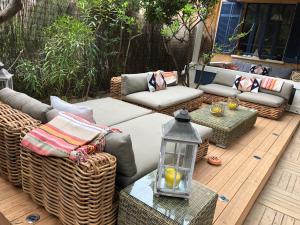 un patio con muebles de mimbre en una terraza de madera en L'Instant - La Capte, en Hyères