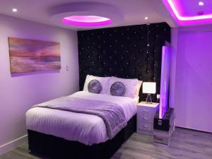 Dormitorio púrpura con cama e iluminación púrpura en Livit Serviced Apartments en Bradford