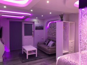 Livit Serviced Apartments في برادفورد: غرفة معيشة مع أريكة وأضواء أرجوانية