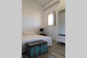 a white bedroom with a bed and a window at Stazzu Bandera in Aglientu