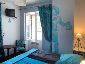 sypialnia z niebieskim łóżkiem i oknem w obiekcie La Bergerie w mieście Le Pouliguen