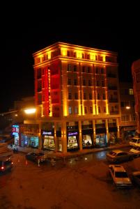 un edificio iluminado con coches estacionados en un estacionamiento en Sapci Prestige Hotel, en Kesan