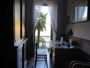 Cette chambre dispose d'un bureau et d'une fenêtre avec un palmier. dans l'établissement La Casa dell'Isola, à Orta San Giulio