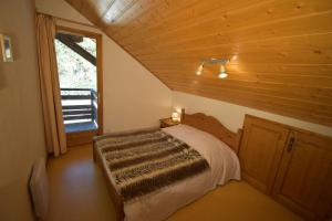 1 dormitorio con 1 cama en una cabaña de madera en VAUJANYLOCATIONS - Les Balcons de Vaujany, en Vaujany