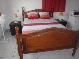 - une chambre avec un lit en bois et 2 tables de chevet dans l'établissement MANIKOU, au Vauclin