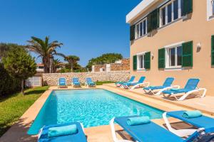 a swimming pool with lounge chairs and a house at Villa Juaneda in Ciutadella