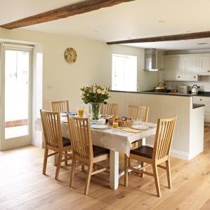 cocina y comedor con mesa y sillas en Manor Farm Courtyard Cottages en Hampstead Norris