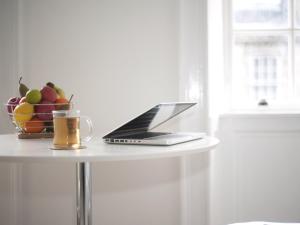 un computer portatile e un cesto di frutta su un tavolo di Marischal Apartments ad Aberdeen