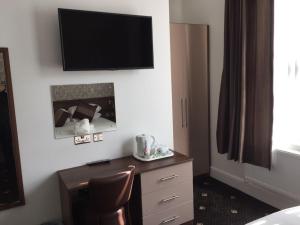 een hotelkamer met een bureau en een televisie aan de muur bij The Marlborough Hotel in Liverpool