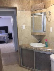 a bathroom with a sink and a mirror and a bed at Agradable* y Cómodo Departamento Familiar (WiFi) in Chihuahua