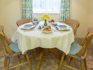 uma mesa com uma toalha de mesa branca e uma tigela de comida em The Cottage Marshwood Farm em Dinton