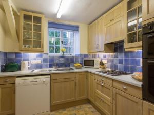a kitchen with wooden cabinets and a sink and a microwave at The Cottage Marshwood Farm in Dinton