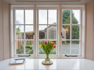 um vaso de flores sentado numa mesa em frente a uma janela em The Cottage Marshwood Farm em Dinton